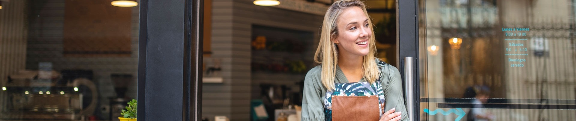 Jonge cafe eigenaar staat met haar armen gekruist bij de voordeur